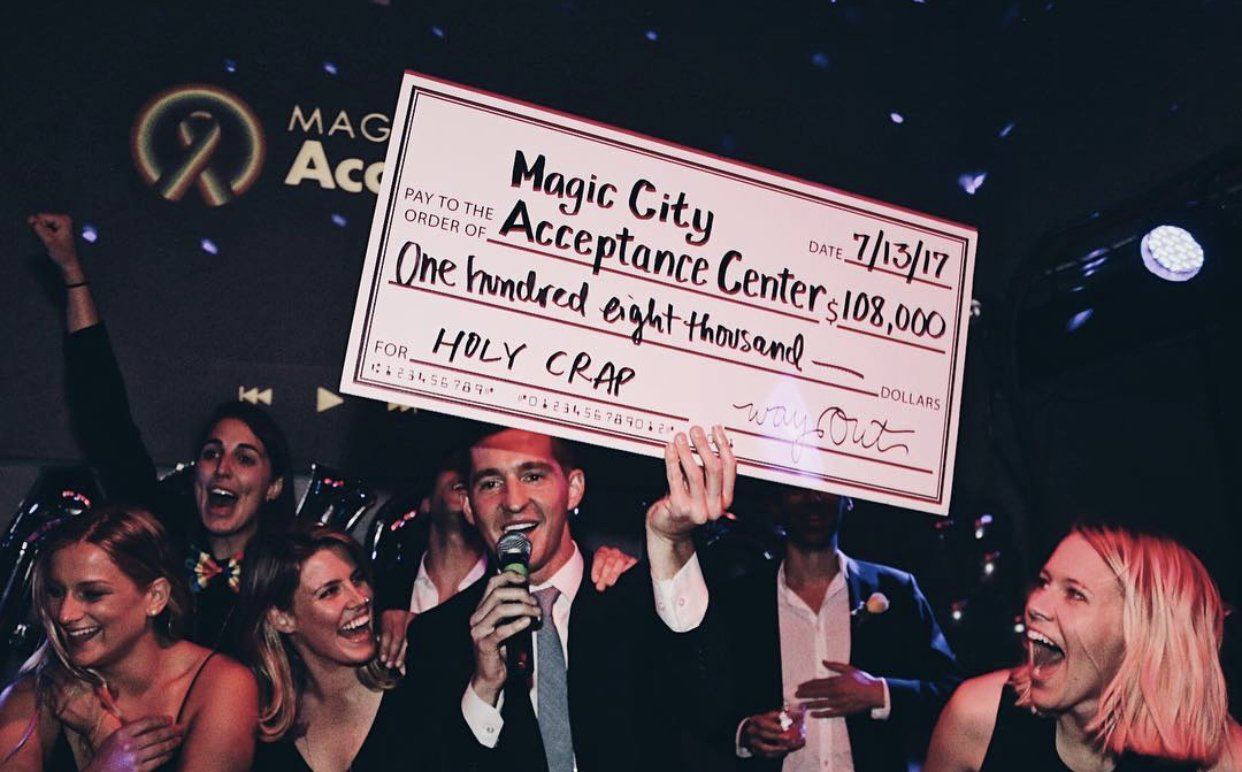 Volunteers cheer as a giant check for Magic City Acceptance Center is held up at the 2017 Bay Area Gayla