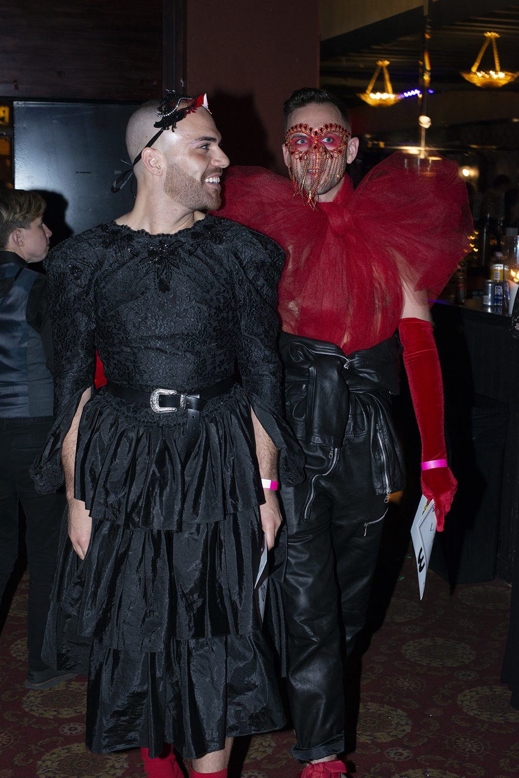 Two guests in black and red looks at the masquerade Gayla