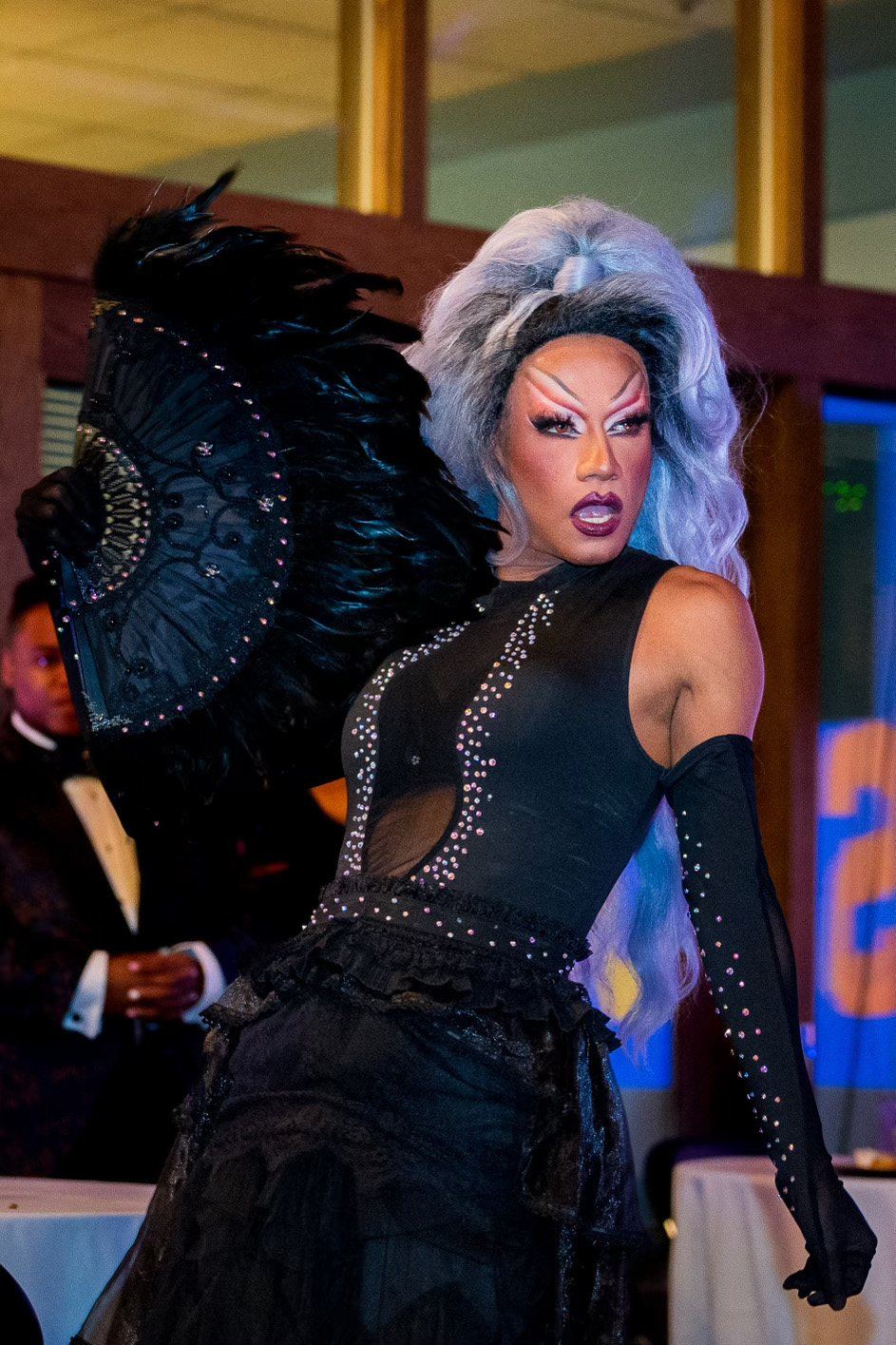 A drag performer in a black feathered look at a wayOUT Seattle event